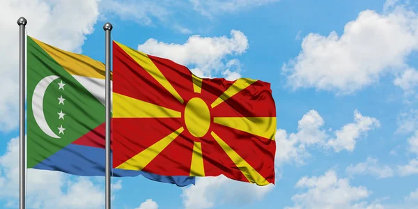 Bandera de las Comoras y Macedonia ondeando en el viento contra el cielo azul nublado blanco juntos. Concepto diplomático, relaciones internacionales . — Foto de Stock
