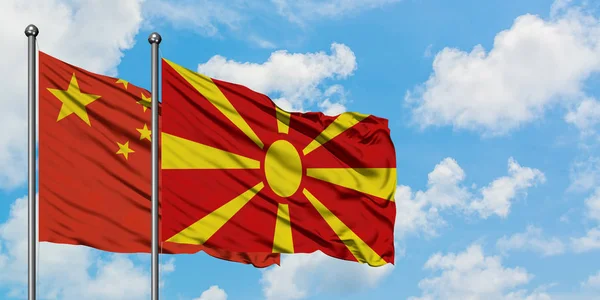 Bandera de China y Macedonia ondeando en el viento contra el cielo azul nublado blanco juntos. Concepto diplomático, relaciones internacionales . — Foto de Stock