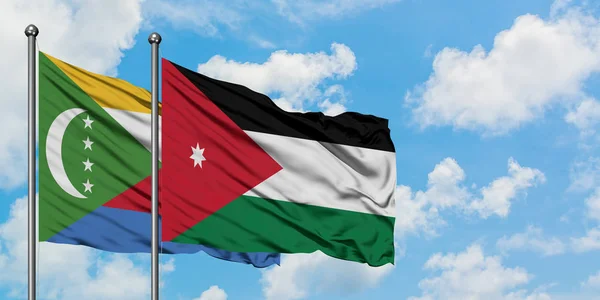 Bandera de las Comoras y Jordania ondeando en el viento contra el cielo azul nublado blanco juntos. Concepto diplomático, relaciones internacionales . — Foto de Stock