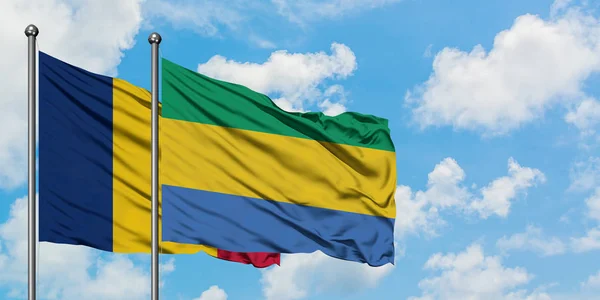 Bandera de Chad y Gabón ondeando en el viento contra el cielo azul nublado blanco juntos. Concepto diplomático, relaciones internacionales . — Foto de Stock