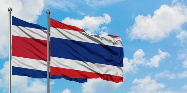 Bandeira da Costa Rica e Tailândia agitando no vento contra o céu azul nublado branco juntos. Conceito de diplomacia, relações internacionais . — Fotografia de Stock