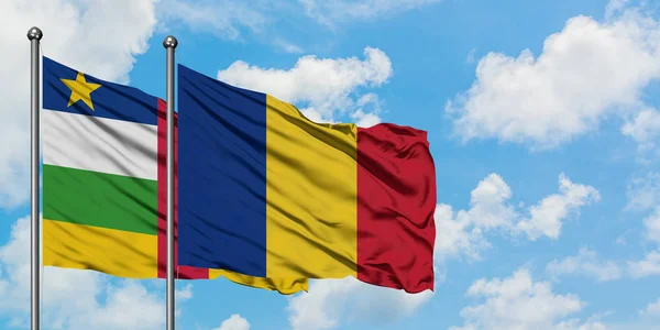 Bandera de República Centroafricana y Rumania ondeando en el viento contra el cielo azul nublado blanco juntos. Concepto diplomático, relaciones internacionales . — Foto de Stock