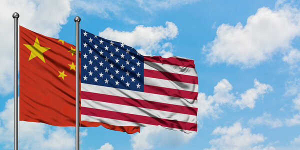 Китай и США вместе размахивают флагом на ветру против белого облачного голубого неба. Концепция дипломатии, международные отношения
.