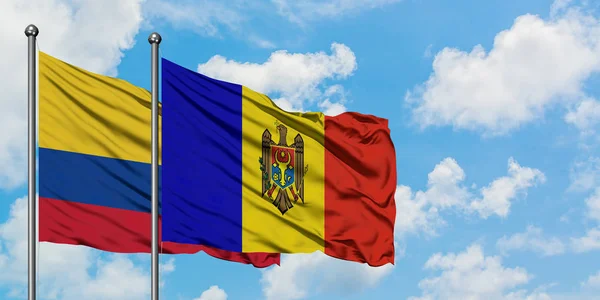 Bandera de Colombia y Moldavia ondeando en el viento contra el cielo azul nublado blanco juntos. Concepto diplomático, relaciones internacionales . — Foto de Stock