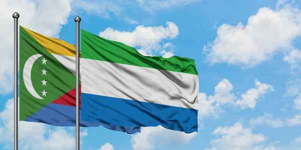 Bandera de las Comoras y Sierra Leona ondeando en el viento contra el cielo azul nublado blanco juntos. Concepto diplomático, relaciones internacionales . — Foto de Stock