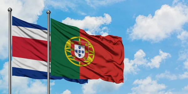 Costa Rica och Portugal flagga vinka i vinden mot vit grumlig blå himmel tillsammans. Diplomatisk koncept, internationella relationer. — Stockfoto