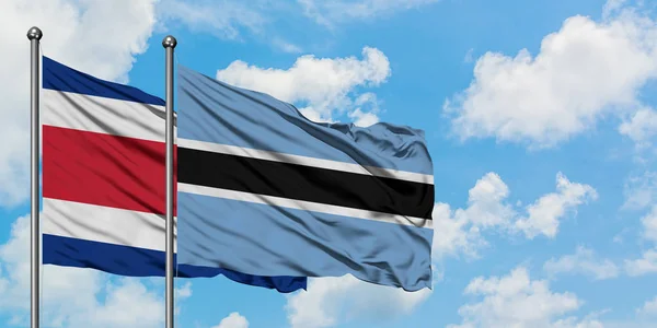 Коста-Ріка і Ботсвана прапор розмахуючи в вітру проти білого хмарного синього неба разом. Концепція дипломатії, міжнародні відносини. — стокове фото