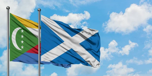 Comoros and Scotland flag waving in the wind against white cloudy blue sky together. Diplomacy concept, international relations.