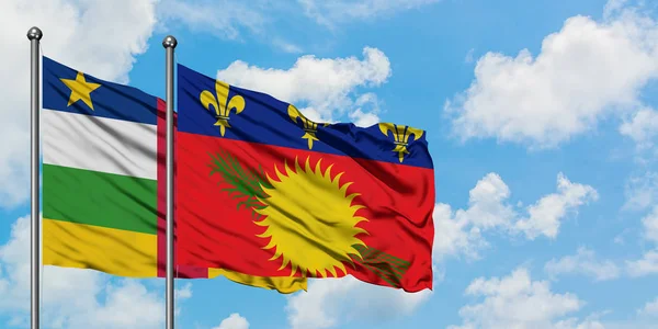 Bandera de la República Centroafricana y Guadalupe ondeando en el viento contra el cielo azul nublado blanco juntos. Concepto diplomático, relaciones internacionales . — Foto de Stock