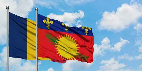 Bandera de Chad y Guadalupe ondeando en el viento contra el cielo azul nublado blanco juntos. Concepto diplomático, relaciones internacionales . — Foto de Stock