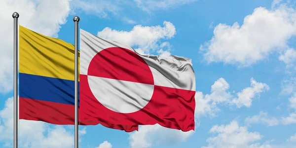 Bandera de Colombia y Groenlandia ondeando en el viento contra el cielo azul nublado blanco juntos. Concepto diplomático, relaciones internacionales . — Foto de Stock