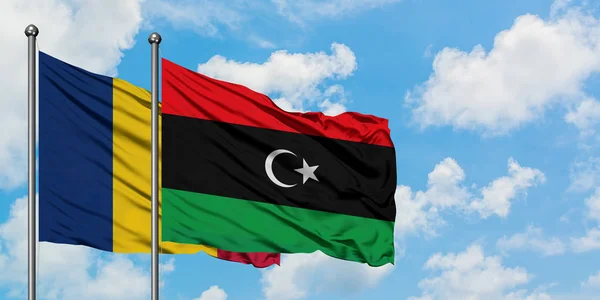 Bandera de Chad y Libia ondeando en el viento contra el cielo azul nublado blanco juntos. Concepto diplomático, relaciones internacionales . — Foto de Stock