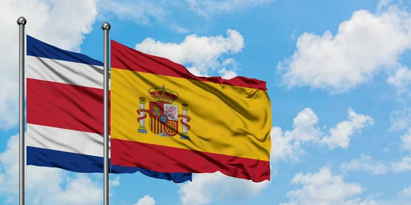 Bandera de Costa Rica y España ondeando en el viento contra el cielo azul nublado blanco juntos. Concepto diplomático, relaciones internacionales . — Foto de Stock