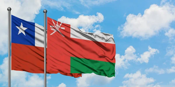 Bandera de Chile y Omán ondeando en el viento contra el cielo azul nublado blanco juntos. Concepto diplomático, relaciones internacionales . — Foto de Stock