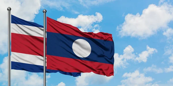 Costa Rica and Laos flag waving in the wind against white cloudy blue sky together. Diplomacy concept, international relations. — Stock Photo, Image