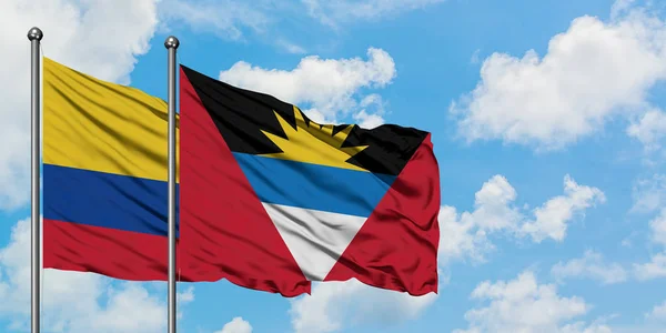 Kolombiya ve Antigua ve Barbuda bayrağı birlikte beyaz bulutlu mavi gökyüzüne karşı rüzgarda sallayarak. Diplomasi kavramı, uluslararası ilişkiler. — Stok fotoğraf