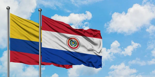 Bandera de Colombia y Paraguay ondeando en el viento contra el cielo azul nublado blanco juntos. Concepto diplomático, relaciones internacionales . — Foto de Stock