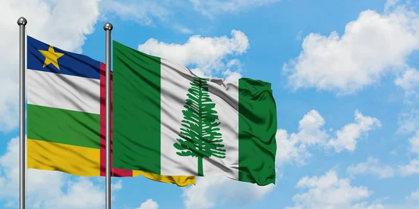 Bandera de la República Centroafricana y la Isla Norfolk ondeando en el viento contra el cielo azul nublado blanco juntos. Concepto diplomático, relaciones internacionales . — Foto de Stock