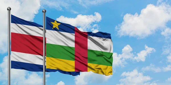 Bandera de Costa Rica y República Centroafricana ondeando en el viento contra el cielo azul nublado blanco juntos. Concepto diplomático, relaciones internacionales . — Foto de Stock