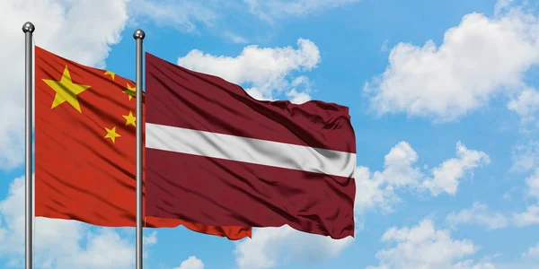 China und Lettland schwenken gemeinsam die Flagge im Wind gegen den wolkenverhangenen blauen Himmel. Diplomatie-Konzept, internationale Beziehungen. — Stockfoto