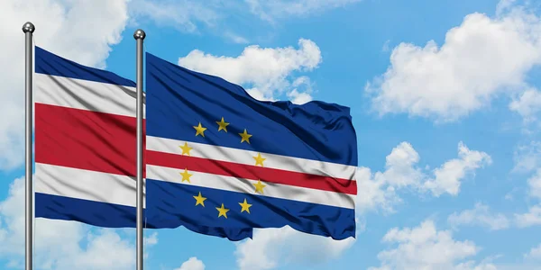 Costa Ricas und Cape Verdes Flagge weht gemeinsam im Wind vor dem wolkenverhangenen blauen Himmel. Diplomatie-Konzept, internationale Beziehungen. — Stockfoto