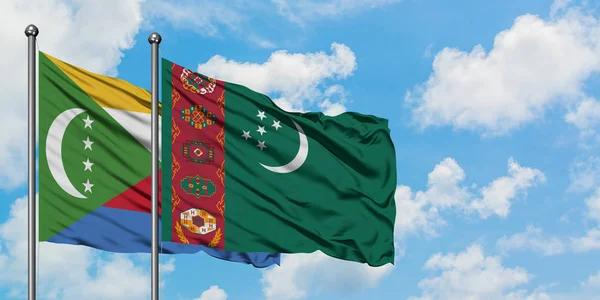 Bandera de las Comoras y Turkmenistán ondeando en el viento contra el cielo azul nublado blanco juntos. Concepto diplomático, relaciones internacionales . — Foto de Stock