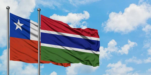 Bandera de Chile y Gambia ondeando en el viento contra el cielo azul nublado blanco juntos. Concepto diplomático, relaciones internacionales . — Foto de Stock