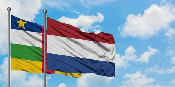 Bandera de República Centroafricana y Países Bajos ondeando en el viento contra el cielo azul nublado blanco juntos. Concepto diplomático, relaciones internacionales . — Foto de Stock
