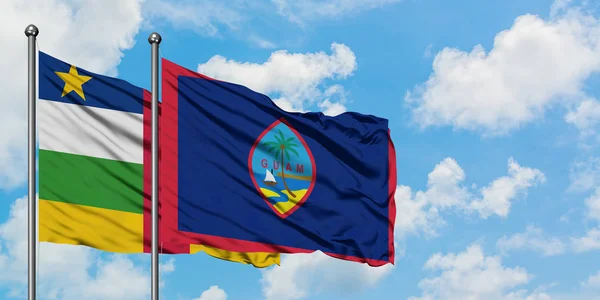 Bandera de la República Centroafricana y Guam ondeando en el viento contra el cielo azul nublado blanco juntos. Concepto diplomático, relaciones internacionales . — Foto de Stock