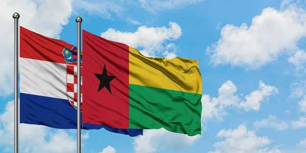 Bandera de Croacia y Guinea Bissau ondeando en el viento contra el cielo azul nublado blanco juntos. Concepto diplomático, relaciones internacionales . — Foto de Stock