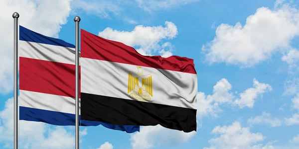Bandera de Costa Rica y Egipto ondeando en el viento contra el cielo azul nublado blanco juntos. Concepto diplomático, relaciones internacionales . — Foto de Stock