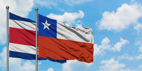 Kostarika a Chilská vlajka mávali ve větru proti bíle zatažené modré obloze. Diplomacie, mezinárodní vztahy. — Stock fotografie