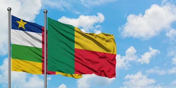 Bandera de Benín y República Centroafricana ondeando en el viento contra el cielo azul nublado blanco juntos. Concepto diplomático, relaciones internacionales . — Foto de Stock