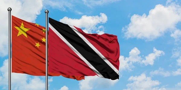 Çin ve Trinidad ve Tobago bayrağı birlikte beyaz bulutlu mavi gökyüzüne karşı rüzgarda sallayarak. Diplomasi kavramı, uluslararası ilişkiler. — Stok fotoğraf