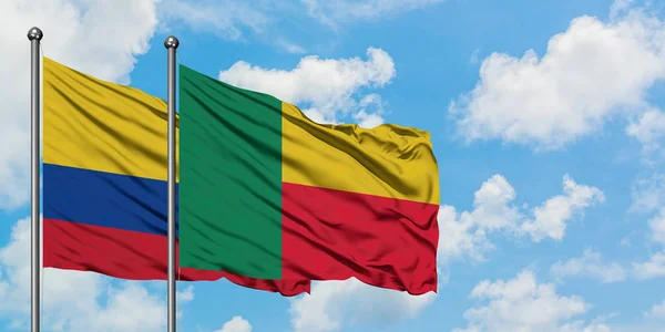 Colombia en Benin vlag zwaaien in de wind tegen witte bewolkte blauwe hemel samen. Diplomatie concept, internationale betrekkingen. — Stockfoto