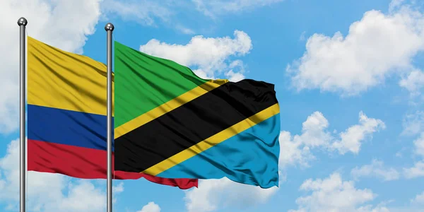 Bandera de Colombia y Tanzania ondeando en el viento contra el cielo azul nublado blanco juntos. Concepto diplomático, relaciones internacionales . — Foto de Stock