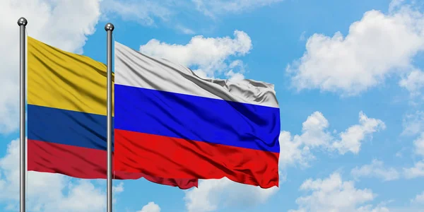 Colombia e Russia sventolano bandiera nel vento contro bianco cielo blu nuvoloso insieme. Concetto di diplomazia, relazioni internazionali . — Foto Stock