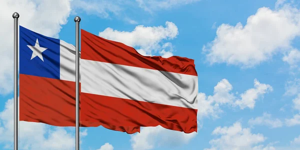 Bandera de Chile y Austria ondeando en el viento contra el cielo azul nublado blanco juntos. Concepto diplomático, relaciones internacionales . — Foto de Stock