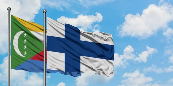 Bandera de las Comoras y Finlandia ondeando en el viento contra el cielo azul nublado blanco juntos. Concepto diplomático, relaciones internacionales . — Foto de Stock