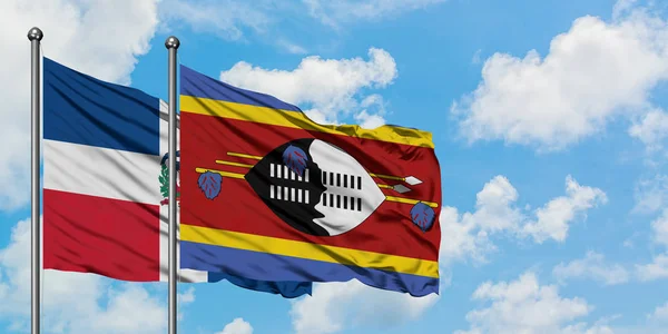 Bandera de República Dominicana y Swazilandia ondeando en el viento contra el cielo azul nublado blanco juntos. Concepto diplomático, relaciones internacionales . — Foto de Stock