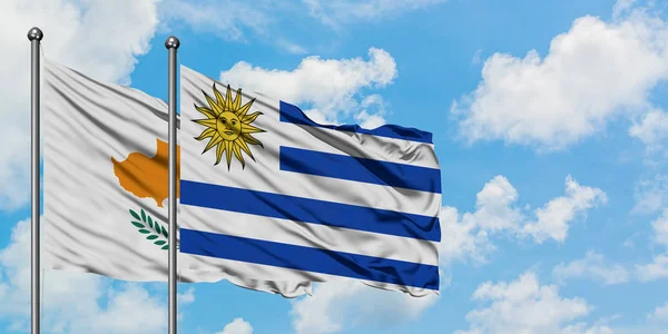 Bandera de Chipre y Uruguay ondeando en el viento contra el cielo azul nublado blanco juntos. Concepto diplomático, relaciones internacionales . —  Fotos de Stock