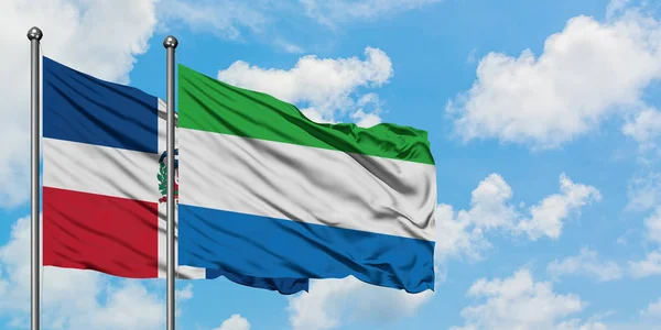 Bandera de República Dominicana y Sierra Leona ondeando en el viento contra el cielo azul nublado blanco juntos. Concepto diplomático, relaciones internacionales . — Foto de Stock