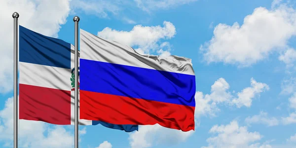 República Dominicana e Rússia bandeira acenando no vento contra o céu azul nublado branco juntos. Conceito de diplomacia, relações internacionais . — Fotografia de Stock