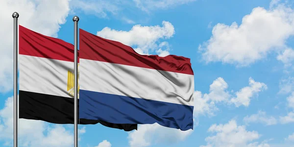 Bandera de Egipto y Holanda ondeando en el viento contra el cielo azul nublado blanco juntos. Concepto diplomático, relaciones internacionales . — Foto de Stock