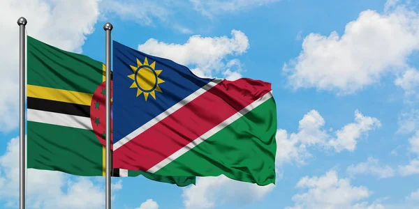 Bandera de Dominica y Namibia ondeando en el viento contra el cielo azul nublado blanco juntos. Concepto diplomático, relaciones internacionales . — Foto de Stock