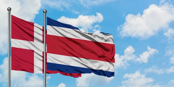 Флаг Дании и Коста-Рики, размахивающий ветром против белого облачного голубого неба. Концепция дипломатии, международные отношения . — стоковое фото