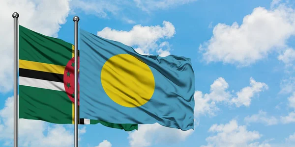 Dominica och Palau flagga viftande i vinden mot vit grumlig blå himmel tillsammans. Diplomatisk koncept, internationella relationer. — Stockfoto
