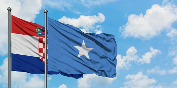 Bandera de Croacia y Somalia ondeando en el viento contra el cielo azul nublado blanco juntos. Concepto diplomático, relaciones internacionales . — Foto de Stock