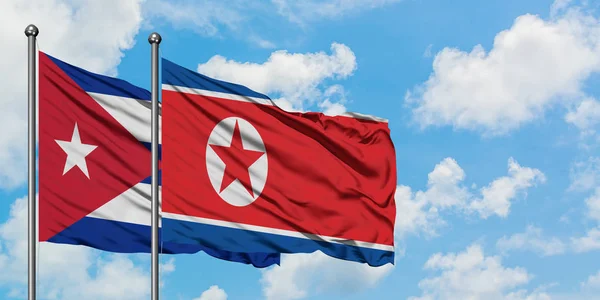 Bandera de Cuba y Corea del Norte ondeando en el viento contra el cielo azul nublado blanco juntos. Concepto diplomático, relaciones internacionales . —  Fotos de Stock