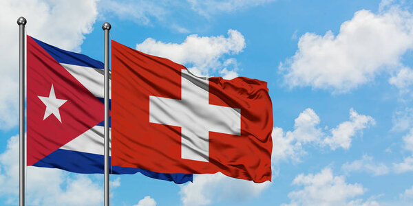 Cuba and Switzerland flag waving in the wind against white cloudy blue sky together. Diplomacy concept, international relations.